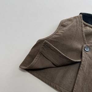 Close-up of brown twill vest featuring detailed stitching and a black round button