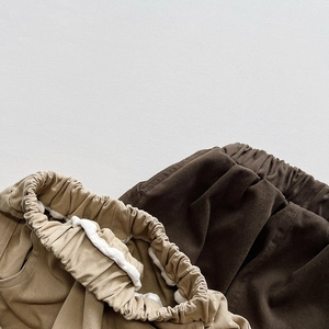 Detail of elastic waistbands in khaki and brown kids cargo pants with twill fabric