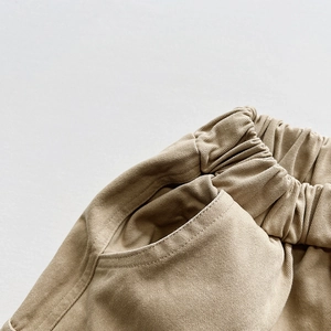 Detail showing elastic waistband and deep side pocket on khaki cotton cargo pants