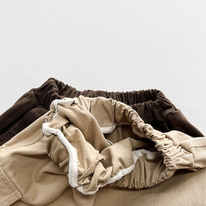 Close-up of elastic waist and twill cotton fabric on children cargo pants in khaki and brown