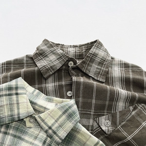 Detail of vintage plaid cotton shirts for kids featuring textured fabric and classic buttons