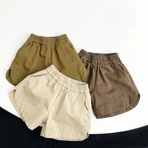 Dettaglio di tre pantaloncini per bambini in cotone e lino verde militare, albicocca e caffè