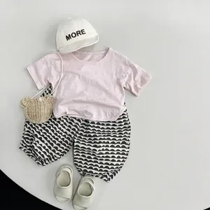 Kids summer outfit with pink cotton T-shirt, wave pattern pants and bear straw bag