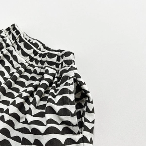 Detail of girls' linen pants with elastic waist, side pockets, and black wave pattern