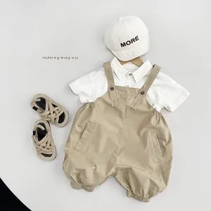 Flat lay of kids summer beige cotton overalls and white short-sleeved polo shirt