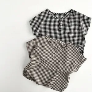 Close-up of black and brown plaid cotton shirts for kids with buttoned necklines