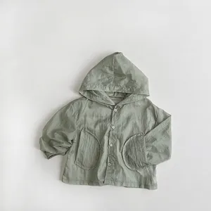 Détail de la veste légère à capuche vert clair avec quatre boutons et poches arrondies