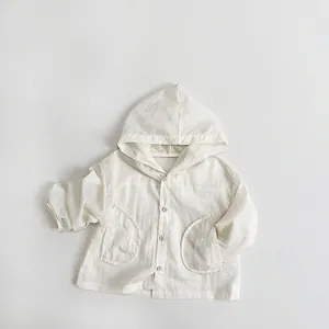 Détail de la veste légère à capuche pour enfant avec boutons et poches semi-circulaires