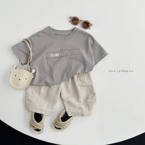 Flat lay of cotton linen kids outfit with grey graphic T-shirt and beige cargo shorts