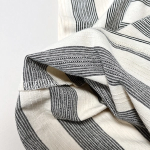 Détail du tissu en maille respirante à rayures noires et blanches sur un t-shirt enfant