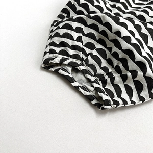 Detail view of girls' linen pants featuring black and white wave patterns and elastic waistband