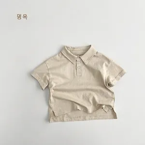 Detailed view of the ribbed cotton fabric and side slit hem on this kids beige polo shirt