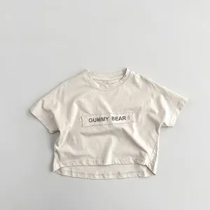 Détail du patch Gummy Bear et du tissu en coton doux sur un T-shirt crème pour enfants