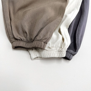 Detail der elastischen Bündchen an Kinderhosen in Braun, Beige und Dunkelgrau aus Baumwolle