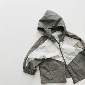 Close-up of windproof hooded jacket with elastic cuffs and gray-white patchwork detail