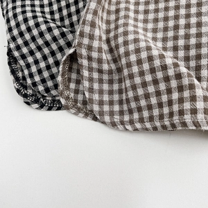 Detail of curved hem and stitching on plaid cotton shirts for children in two colors