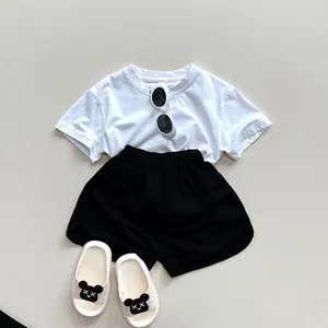Minimalist kids summer set featuring white cotton t-shirt and black casual shorts with sandals