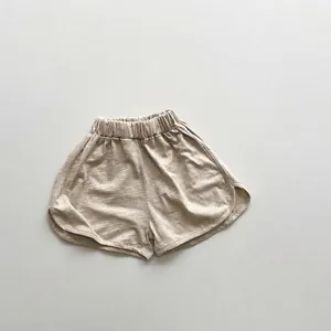 Detailed shot of oat beige cotton shorts featuring elastic waist and dolphin hem design