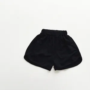 Detail view of children's black cotton shorts featuring elastic waist and curved hems