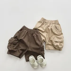 Flat lay of boys cotton cargo shorts in brown and khaki with soft summer sandals
