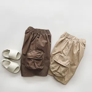 Detailed flat lay of kids cotton cargo shorts in brown and khaki with large round pockets