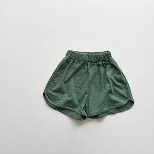 Close-up of dark green cotton shorts with slub texture, elastic waist and curved hem details
