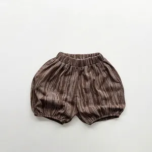 Detail view showing elastic waistband and brown wood grain print on cotton kid shorts