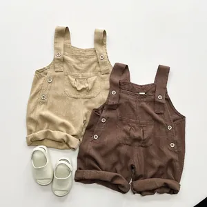 Détail de la salopette enfant en mélange de lin avec boutons en bois et poches plissées