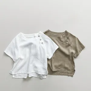 Detail of linen kids' T-shirts showing side-button collars and split hems in a soft style
