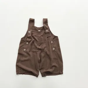Détails d'une salopette bébé en coton lin marron foncé avec boutons en bois et petite poche