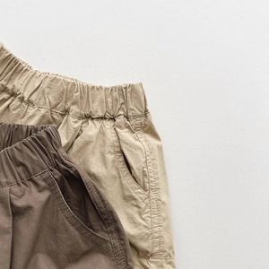 Detail of elastic waist and side pockets on cotton utility shorts in khaki and brown