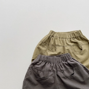 Detail of kids cotton lantern shorts featuring elastic waist and olive green fabric texture