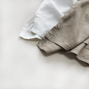 Detail of the hem stitching and natural cotton linen texture on kids' summer top