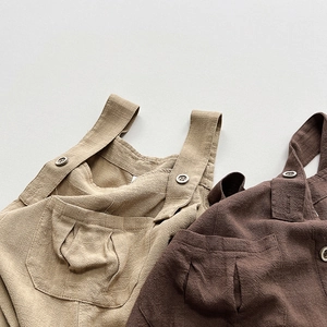Détail de salopettes pour bébé en coton et lin kaki et marron avec de grandes poches