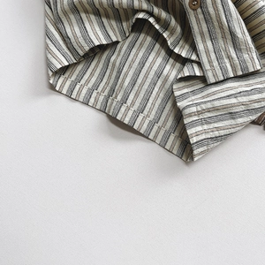 Gros plan sur la texture rayée en coton avec coutures précises et bouton en résine