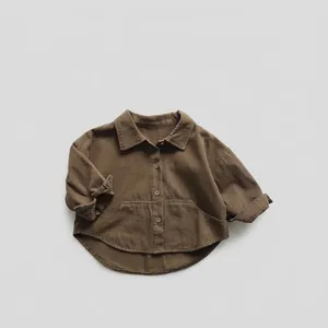 Détail d'une chemise en velours côtelé marron pour enfants avec boutons et grandes poches