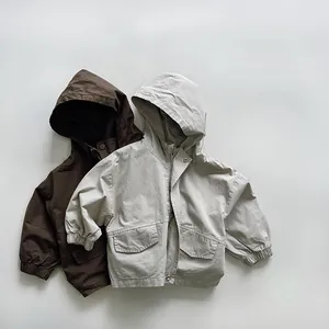 Detail view of neutral-toned hooded jackets for kids featuring large pockets and metal buttons