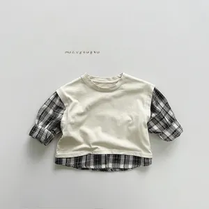 Detail eines Baby-Lagen-T-Shirts mit cremefarbener Weste und karierten Ärmeln