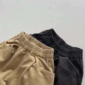 Detail of elastic waistbands and side pockets on tan and black kids' casual pants