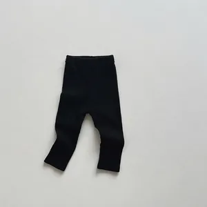 Detail of children's black ribbed leggings featuring a wide elastic comfort waistband