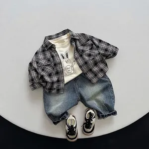 Boy's autumn outfit with grey plaid shirt, rabbit print t-shirt and blue denim jeans
