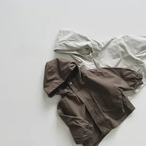 Detail of kids hooded jackets with utility pockets and snap buttons in brown and beige