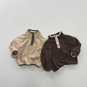 Flat lay detail of two soft fleece sweaters for children with buttoned stand-up collars