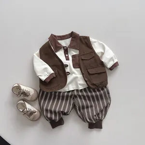 Dettaglio dell'abbigliamento bimbo con gilet marrone, polo bianca e pantaloni a righe