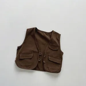 Dettaglio del gilet in cotone marrone per bambini con tre tasche e chiusura a bottoni