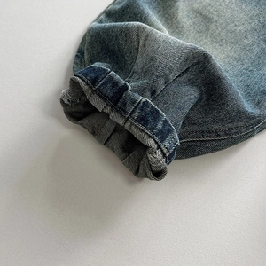 Vue macro d'un jean bleu délavé vintage avec des ourlets élastiques et des coutures fines