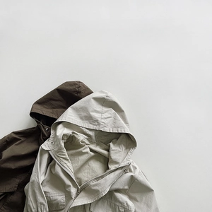 Detail view of neutral hooded jackets in brown and beige canvas with cargo pockets