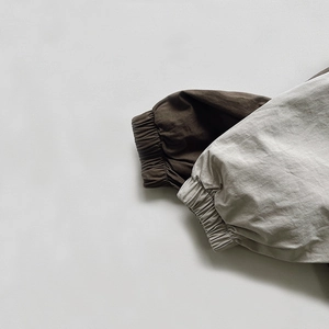 Detail of elastic cuffs on children's jackets in dark brown and light grey high-density cotton