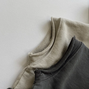 Dettaglio ravvicinato dello scollo a bordo vivo su felpe in cotone beige e grigio