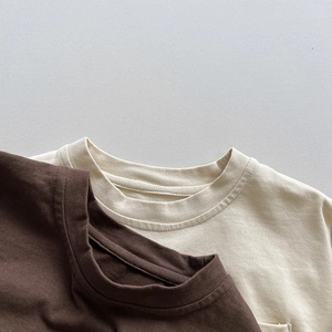Détail du col rond côtelé sur un t-shirt enfant en coton de couleur crème et marron